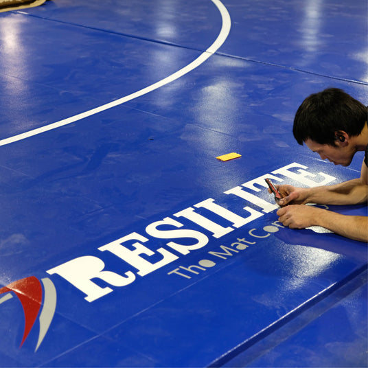A Resilite Mat Craftsman carefully prepares a Classic Wrestling Mat