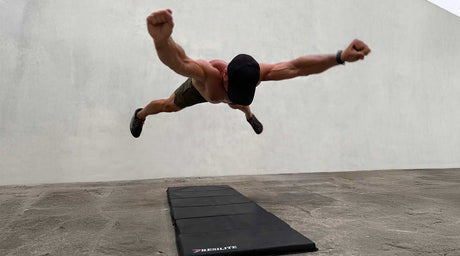 Dad performing a superhero-style jump over an OmniMat™ workout mat during a home fitness session