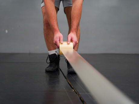 Hands applying wrestling mat tape across seam for secure fit