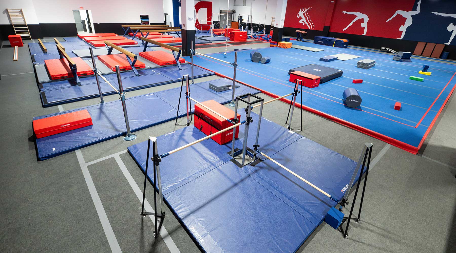 Wide-angle view of the Dominique Dawes Gymnastics & Ninja Academy featuring Resilite mats, pads, and ninja training equipment throughout the facility.