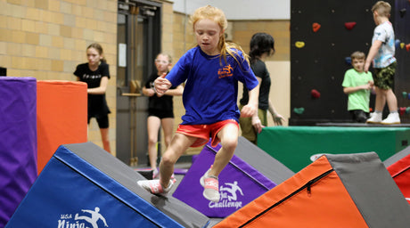 Kids training on youth ninja gym obstacles with crash mats and safety padding