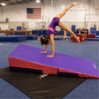 A gymnast in a purple leotard performs a handstand on a wedge gymnastics mat placed on the non-skid Resilite Mat Grip 